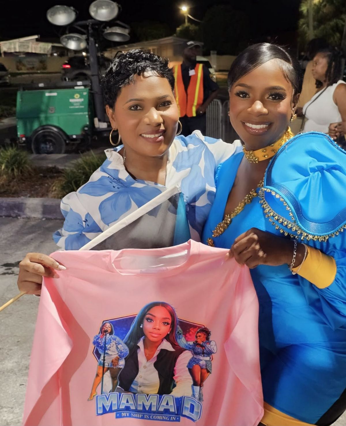 Mama D with a fan holding a My Ship Is Coming In t-shirt