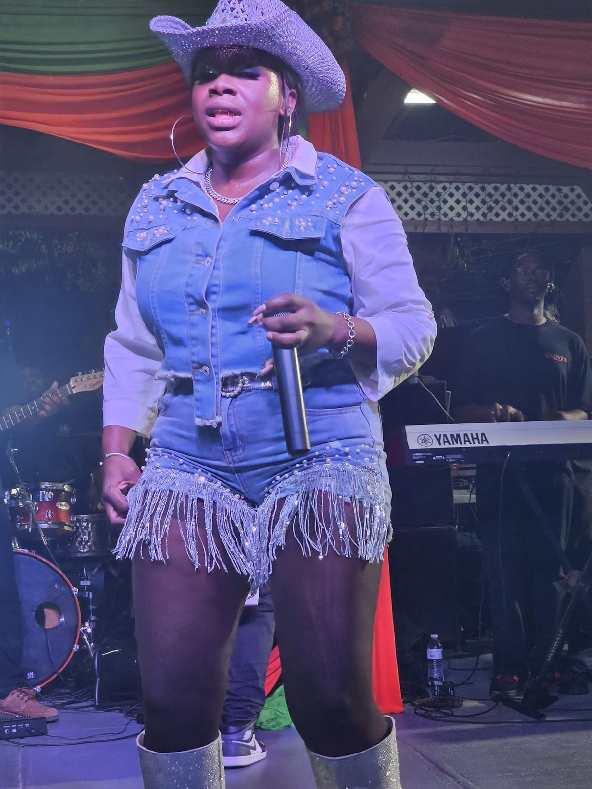 Mama D on stage in a denim outfit holding the microphone at her side