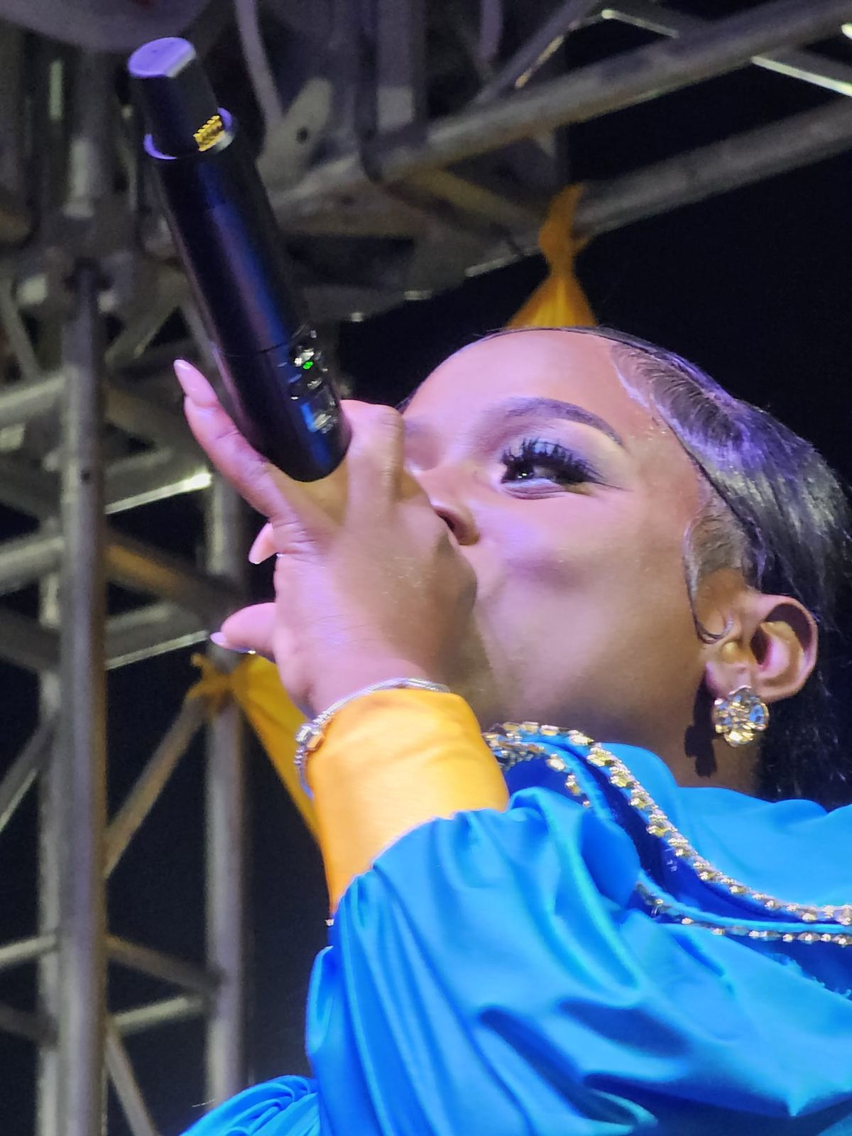 Close up of Mama D singing in a blue and gold outfit