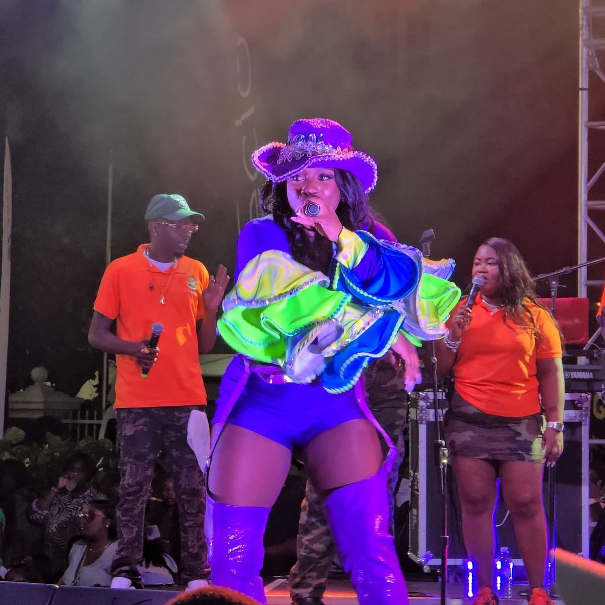 Mama D performing in a purple sequined hat and a neon green stage outfit
